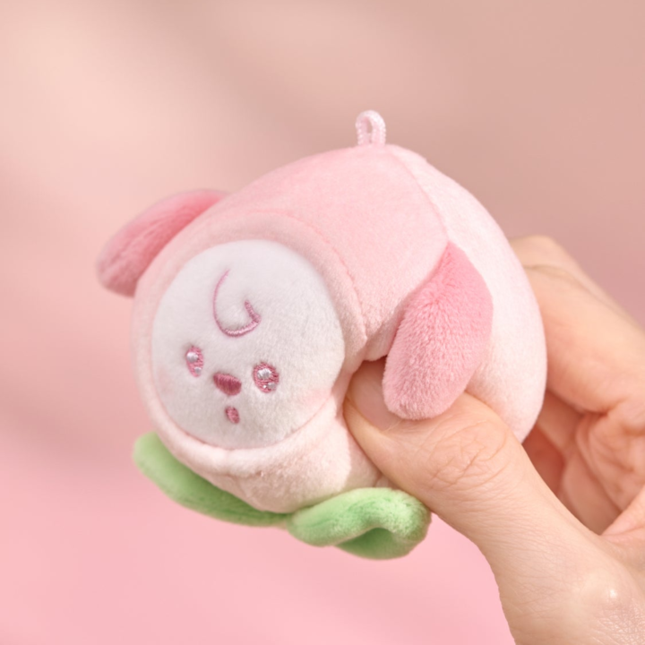 BT21 Peach Holic CHIMMY stress ball being gently squeezed by hand on a pink background