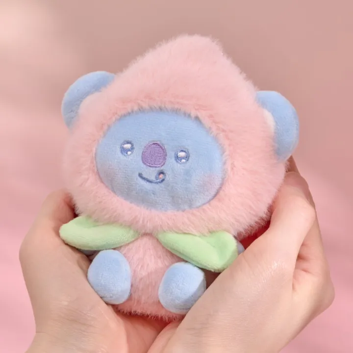 BT21 Peach Holic KOYA plush keyring held in two hands on a pink background