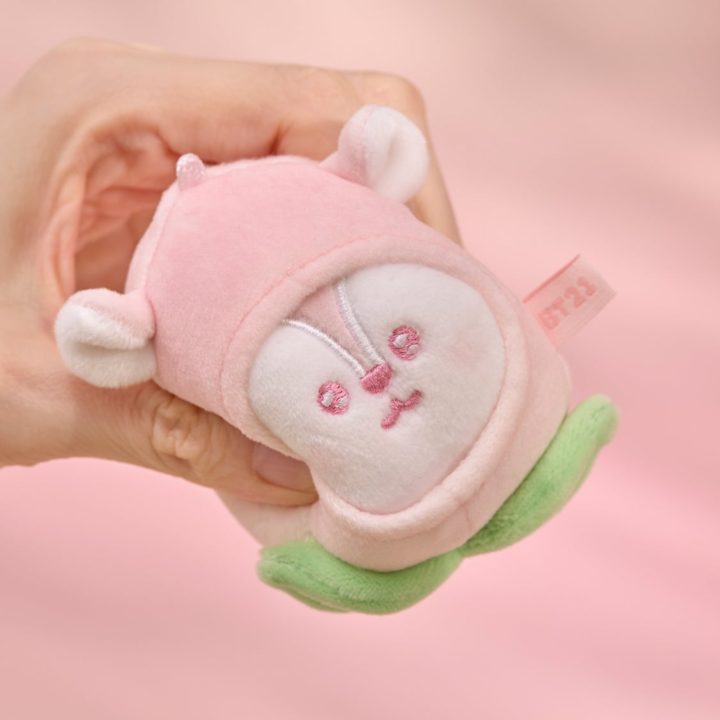 BT21 Peach Holic MANG stress ball being gently squeezed by hand on a pink background
