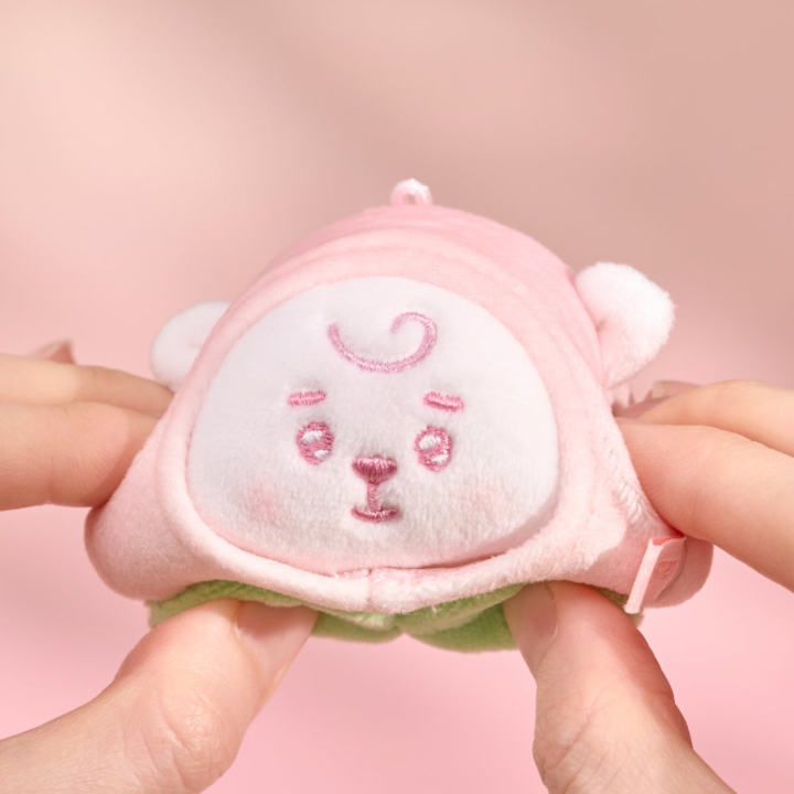 BT21 Peach Holic RJ stress ball being gently squeezed by hand on a pink background