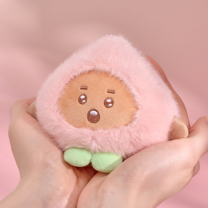 BT21 Peach Holic SHOOKY plush keyring held in two hands on a pink background