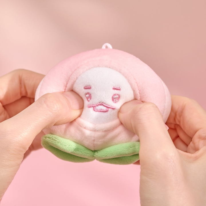 BT21 Peach Holic SHOOKY stress ball being gently squeezed by hand on a pink background