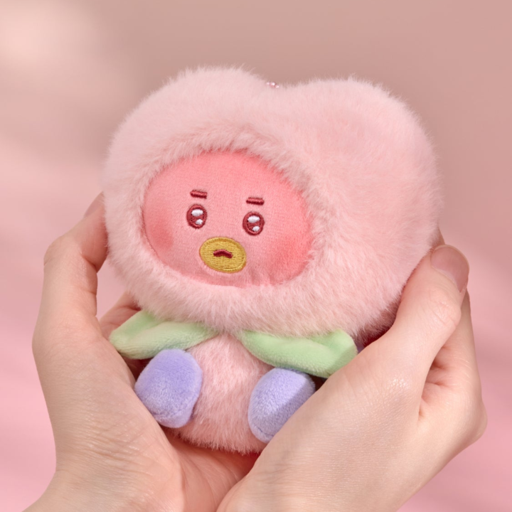BT21 Peach Holic TATA plush keyring held in two hands on a pink background